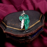 Green and silver pendant on a dark leather surface with a red fabric background