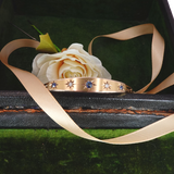 Rose gold ring with blue and white gemstones on a black box with a white rose and ribbon.
