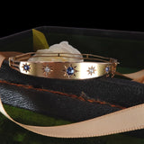 Gold bracelet with gemstones on a black fabric background