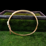 Gold bracelet on a green textured surface with a dark background