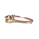 Gold bracelet with a textured band and spherical elements on a white background