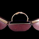 Vintage-style handbag with a gold handle on a black background