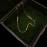 Gold chain necklace on a green velvet surface