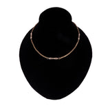 Gold bracelet on a black velvet stand against a white background