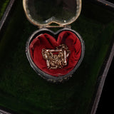 Decorative brooch in a heart-shaped box with red lining on a dark background