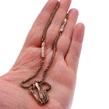 Gold chain necklace held in a hand against a white background