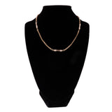 Gold necklace on a black mannequin bust against a white background