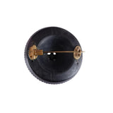 Black button with gold pin on a white background