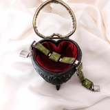 Heart-shaped jewelry box with green stones on a white fabric background