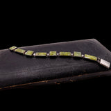 Bracelet with green stones on a black leather surface