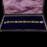 Set of green gemstone cufflinks in a black case with purple interior