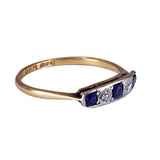 Gold ring with sapphire and diamond stones on a white background