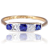 Gold ring with blue gemstones and diamonds on a white background