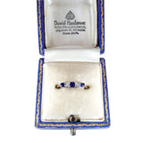 Diamond and sapphire ring in a David Henderson jewelry box on a white background