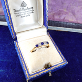 Gold ring with blue stones in a David Henderson jewelry box on a blue background