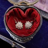 Heart-shaped jewelry box with red fabric interior containing silver heart-shaped earrings.