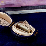 Gold ring in an open jewelry box with a purple fabric background