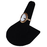 Gold ring with a cameo on a black stand against a white background