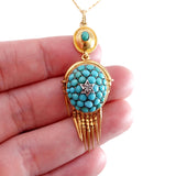 Turquoise and gold pendant held in a hand against a white background