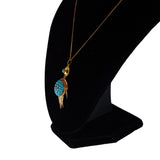 Necklace with a turquoise pendant on a black stand against a white background
