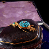 Vintage brooch with turquoise stones and gold accents on a dark leather case.