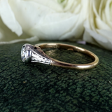 Silver ring with a diamond on a green textured surface with white flowers in the background