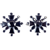 Pair of black and silver star-shaped earrings on a white background
