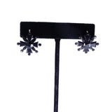 Pair of black star-shaped earrings on a black velvet stand against a white background