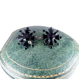 Black star-shaped earrings on a green jewelry box
