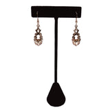 Pair of earrings on a black earring stand against a white background