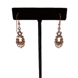 Pair of gold earrings on a black earring stand against a white background