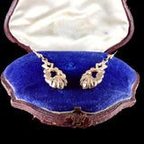 Pair of gold earrings in a jewelry box with blue interior