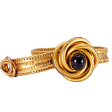 Gold bracelet with a central gemstone on a white background