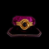 Gold ring with a black gemstone in a purple cushion box on a black background