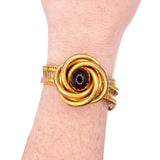 Gold bracelet with a central brown stone on a wrist against a white background