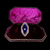 Diamond and blue stone brooch in a purple velvet box on a black background