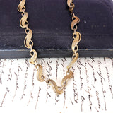 Gold chain necklace on a textured surface with text