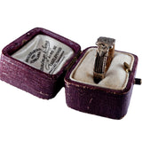 Gold ring in an open purple jewelry box on a white background