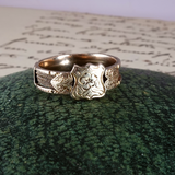 Silver ring with intricate designs on a textured green surface