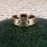 Silver ring with a detailed design on a textured green surface