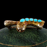 Gold brooch with turquoise stones on a green cushion