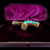 Gold brooch with turquoise stones on a purple velvet background