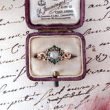 Vintage brooch with emerald stones in a purple box on an old letter background
