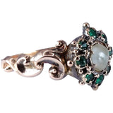 Gold ring with emeralds and a pearl on a white background