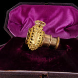 Gold ornate object on purple velvet in a black box