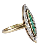 Gold ring with emerald and diamond design on a white background