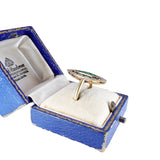 Gold ring with green gemstone in a blue jewelry box