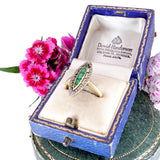 Gold ring with emerald and diamond in a blue jewelry box with pink flowers.