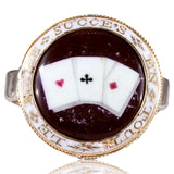 Ring with a central circular design featuring a card with hearts and a cross, surrounded by gold and white text on a white background.