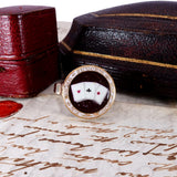 Ring with playing card design on a surface with text and vintage box
